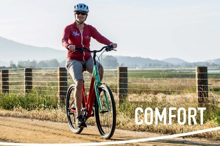 Person in red shirt and helmet rides a bike on a rural path, with 'COMFORT' text overlay.